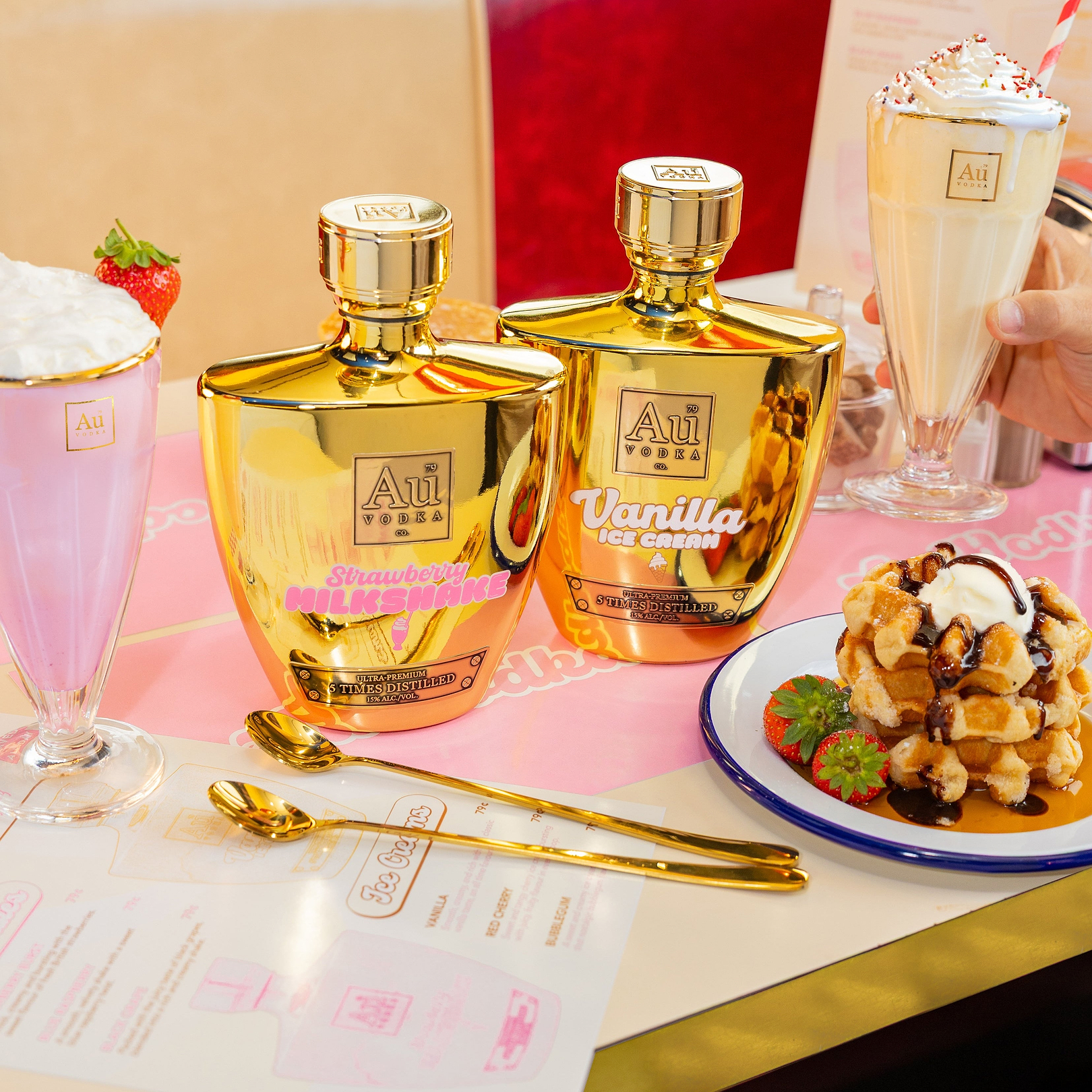 Au Vodka Strawberry Milkshake and Vanilla Ice Cream bottles with milkshakes and waffles on a table