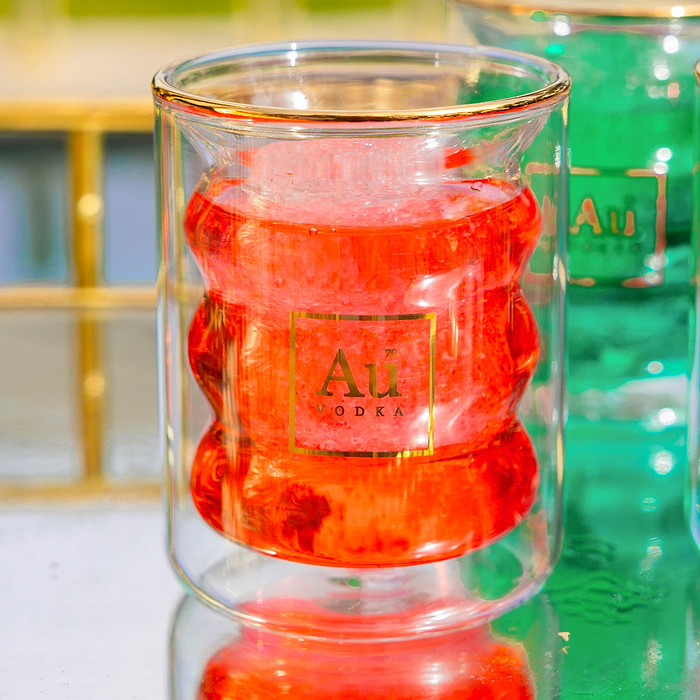 Au Vodka branded double walled glassware containing a red liquid and ice