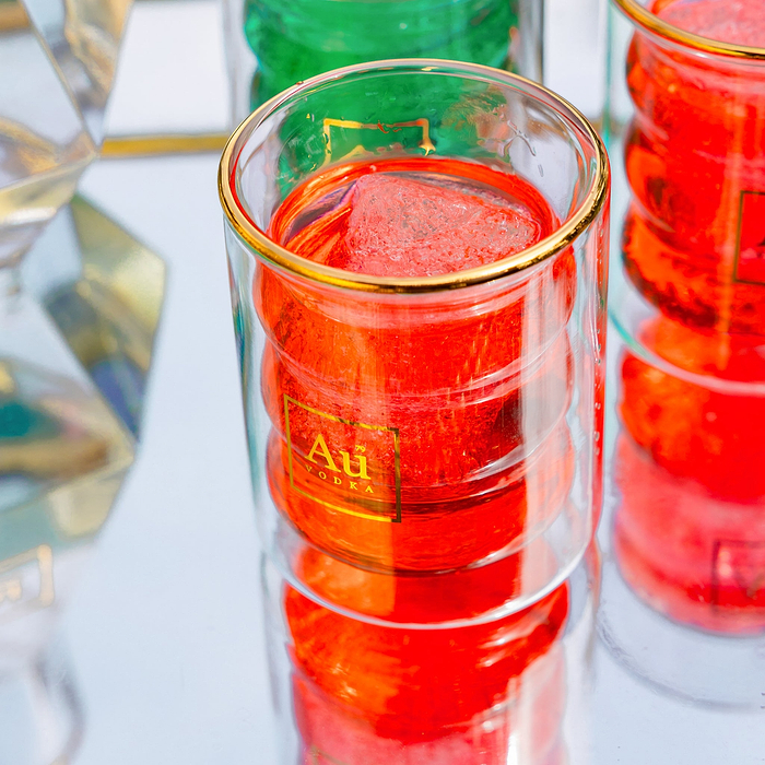 Au Vodka branded double walled glassware containing red liquid and ice
