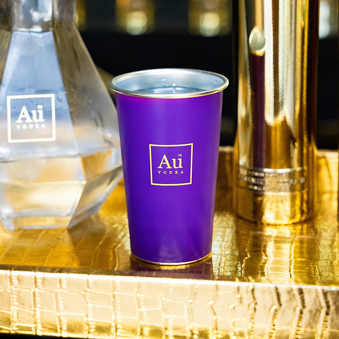 Au Vodka USA purple merchandise cup with gold logo on a gold crocodile-textured surface