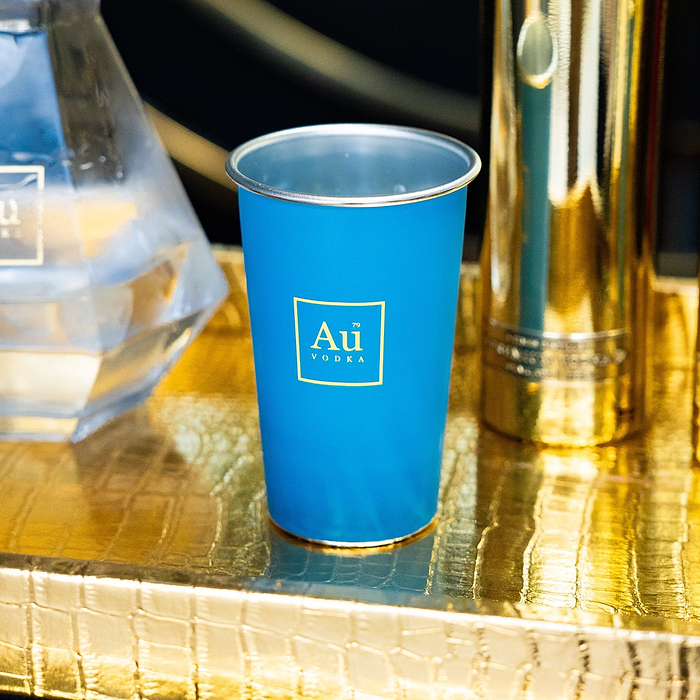 Au Vodka USA blue merchandise cup with gold logo on a gold textured surface
