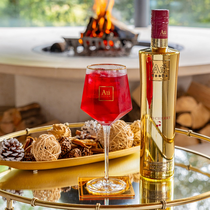 Au Vodka Red Cherry bottle and branded glassware filled with red cocktail on a gold tray