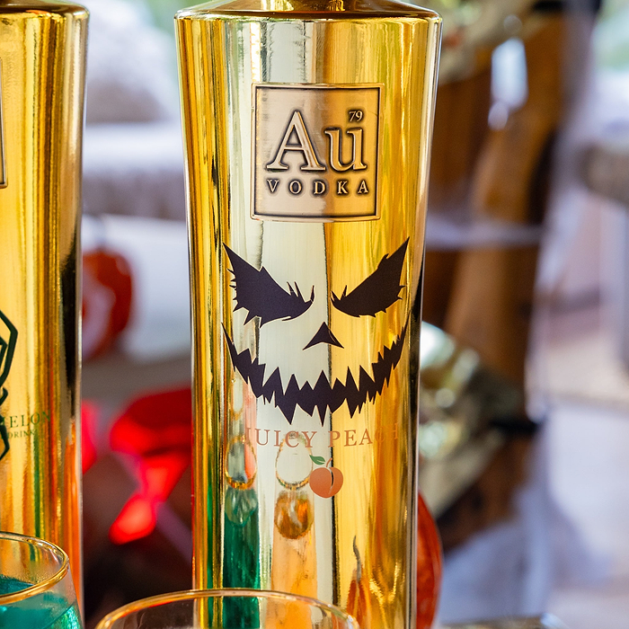 Gold bottle of Au Vodka with a Halloween design on a blurred background