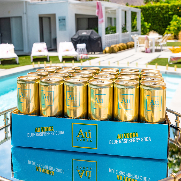 Au Vodka Blue Raspberry Soda cans in a blue box on a reflective surface by a pool