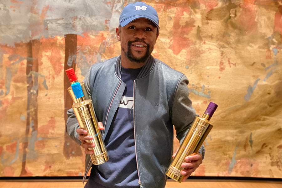 Floyd Mayweather holding two gold bottles of Le Chemin du Roi Brut and Rosé