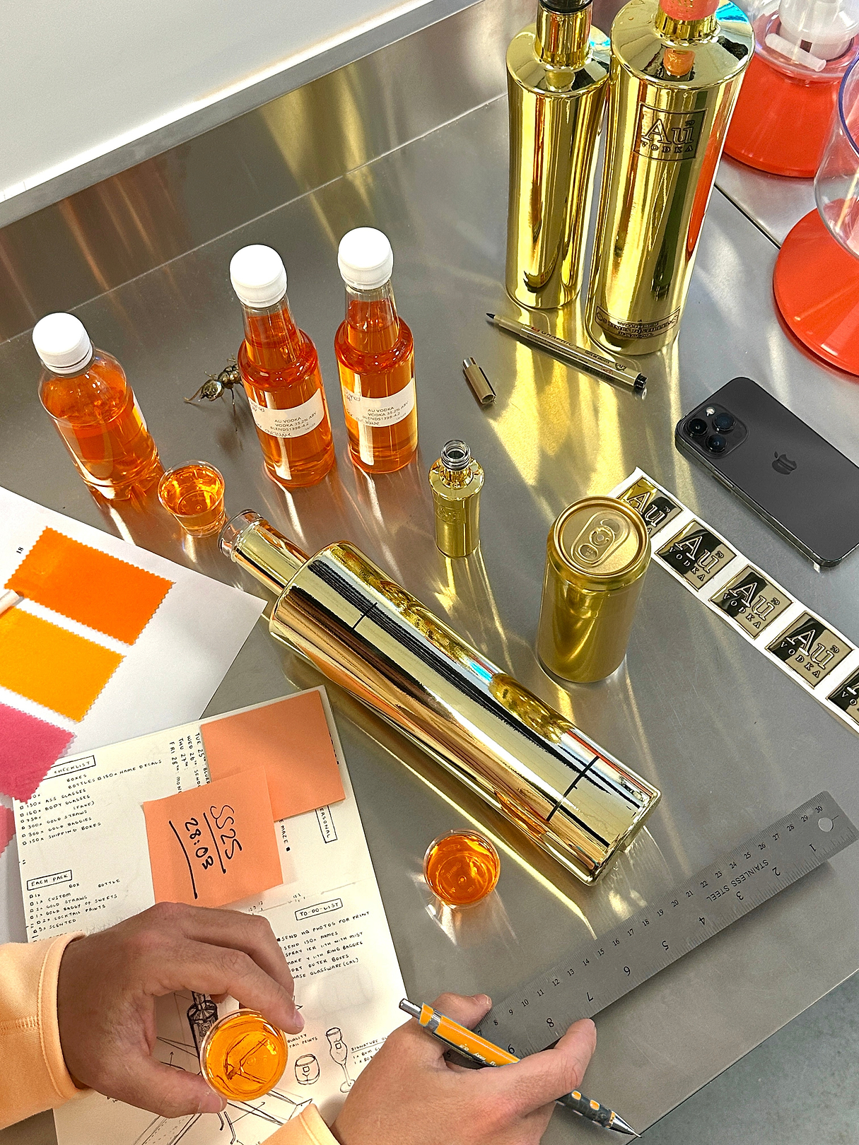 Au Vodka bottles and cans with orange liquid samples on a metal workspace