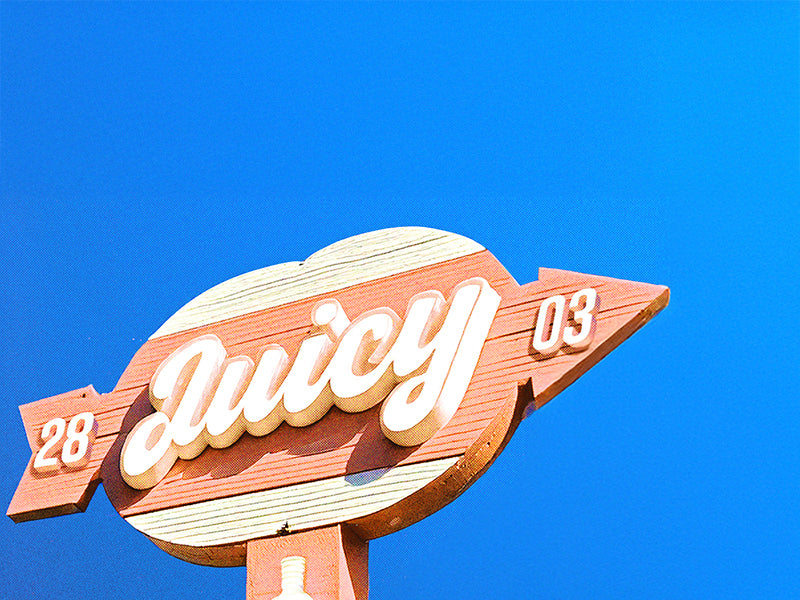 Juicy brand arrow sign against a bright blue sky