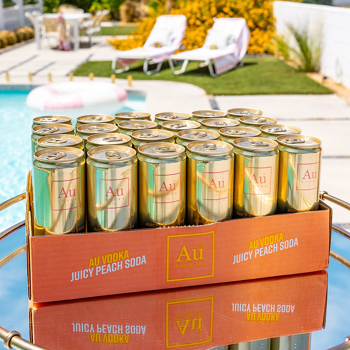 Au Vodka Juicy Peach Soda Cocktail Cans in a case by a pool