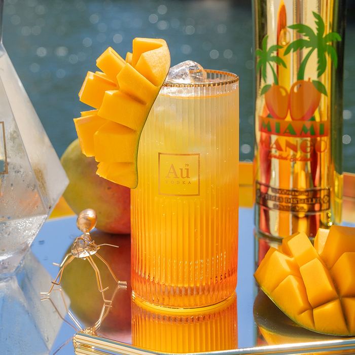 Au Vodka Miami Mango cocktail with mango garnish and a bottle of Au Vodka Miami Mango