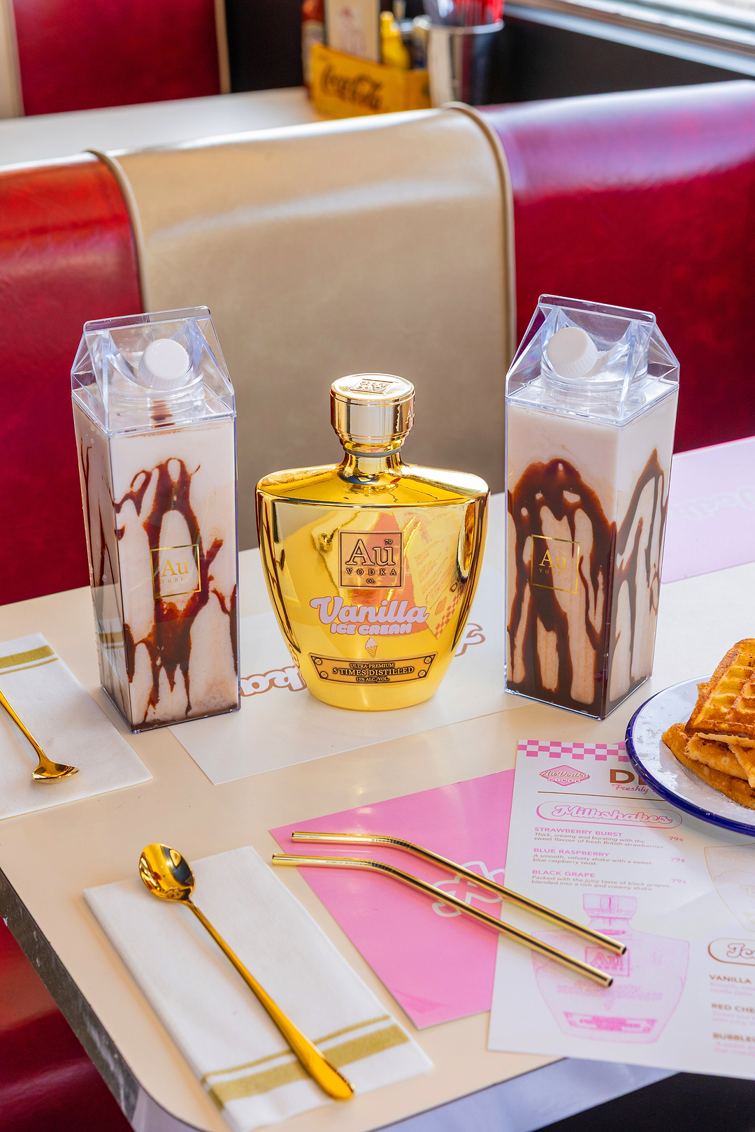 Au Vodka Vanilla Ice Cream bottle with two milkshakes in carton style glasses on a diner table