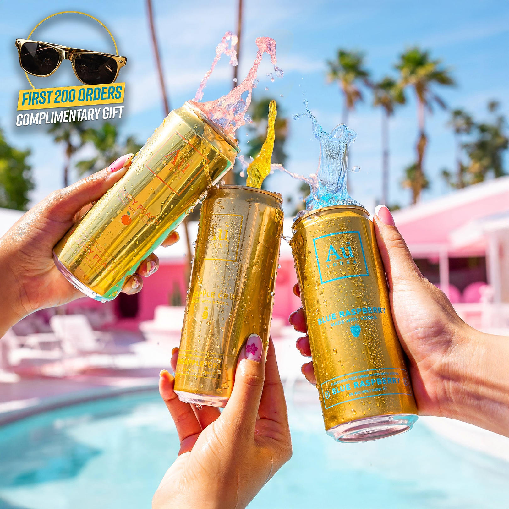 Three gold Au Vodka cans splashing with liquid held by hands by a pool with a promotional sunglasses graphic