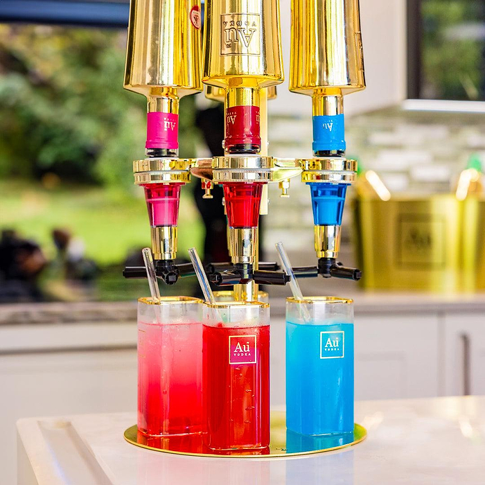 Au Vodka merchandise triple bottle dispenser with red and blue drinks in branded glasses