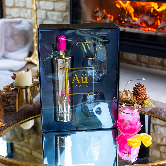 Au Vodka Red Cherry gift pack containing a bottle and two glasses on a mirrored table by a fireplace