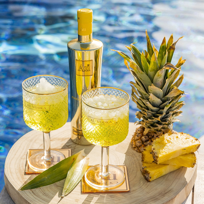Au Vodka USA Juicy Peach bundle with two cocktails and pineapple by a pool