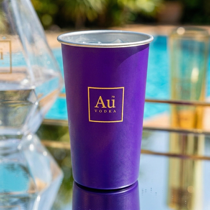 Au Vodka USA purple merchandise cup with gold logo, filled with ice and a clear liquid