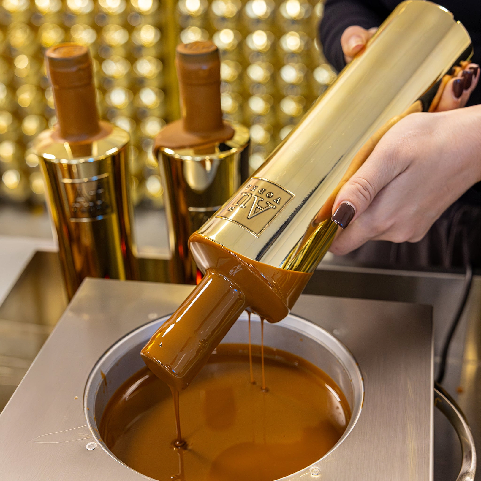 Au Vodka bottle being dipped into a vat of melted chocolate