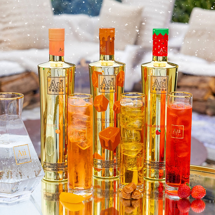 Au Vodka Juicy Peach Sticky Toffee and Strawberry Burst bottles with matching cocktails and fresh fruit