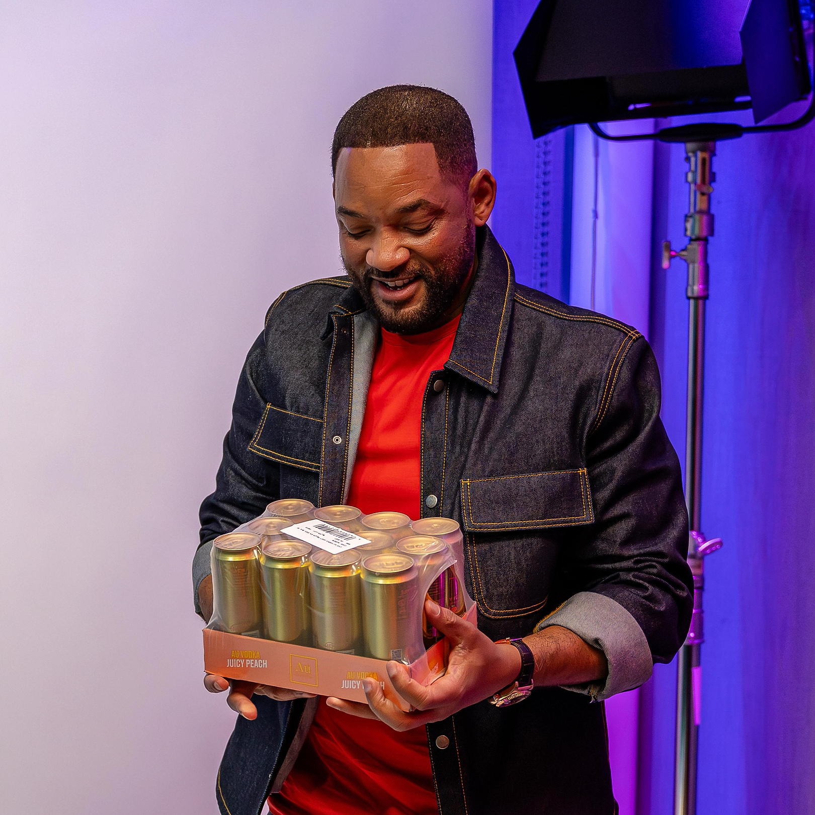 Will Smith holding a pack of Au Vodka Juicy Peach cans