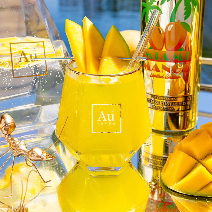 Close up of Au Vodka USA Mango Passion drink with mango slices and bottle