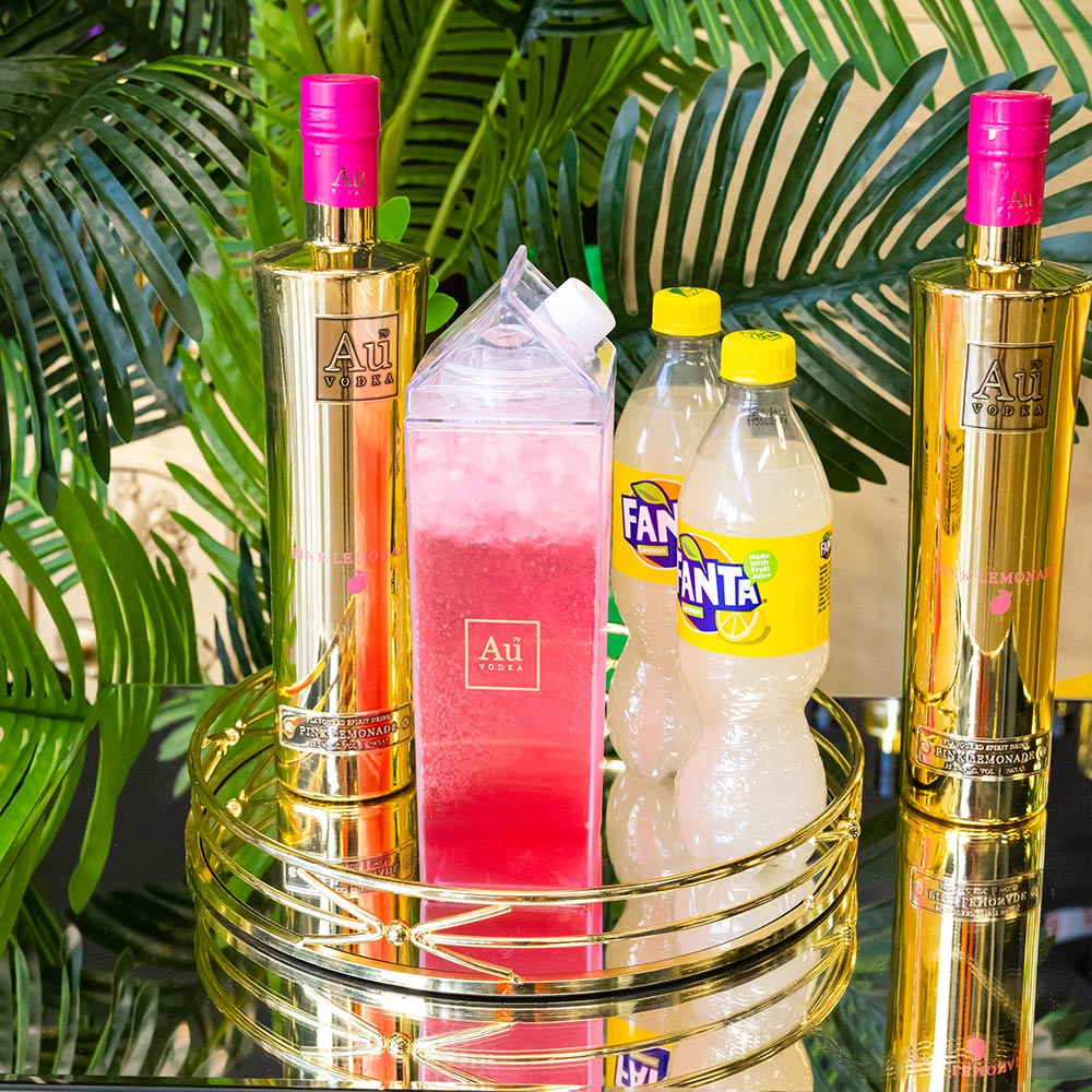 Au Vodka bottles next to a clear carton of red cocktail and bottles of Fanta
