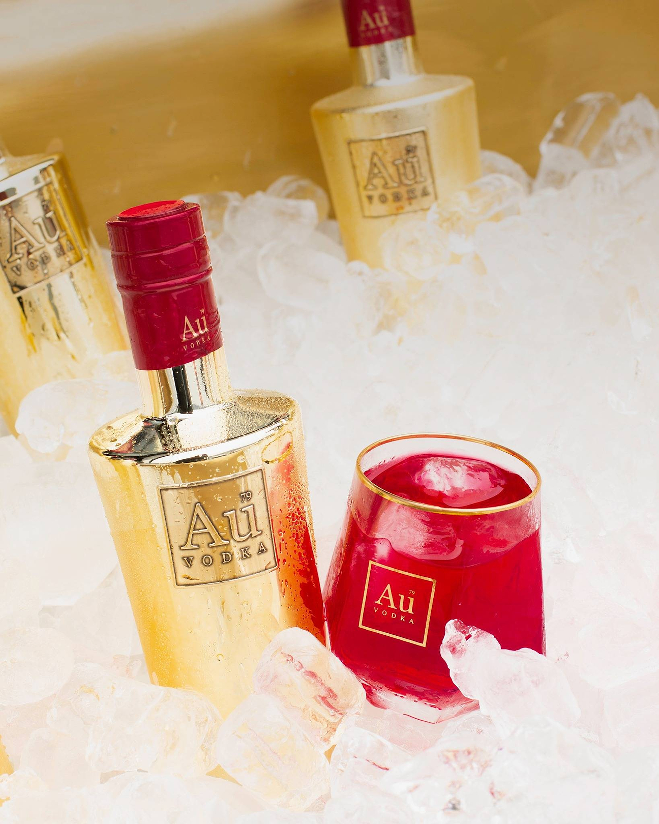 Au Vodka gold bottles and a glass of red cocktail in a bucket of ice
