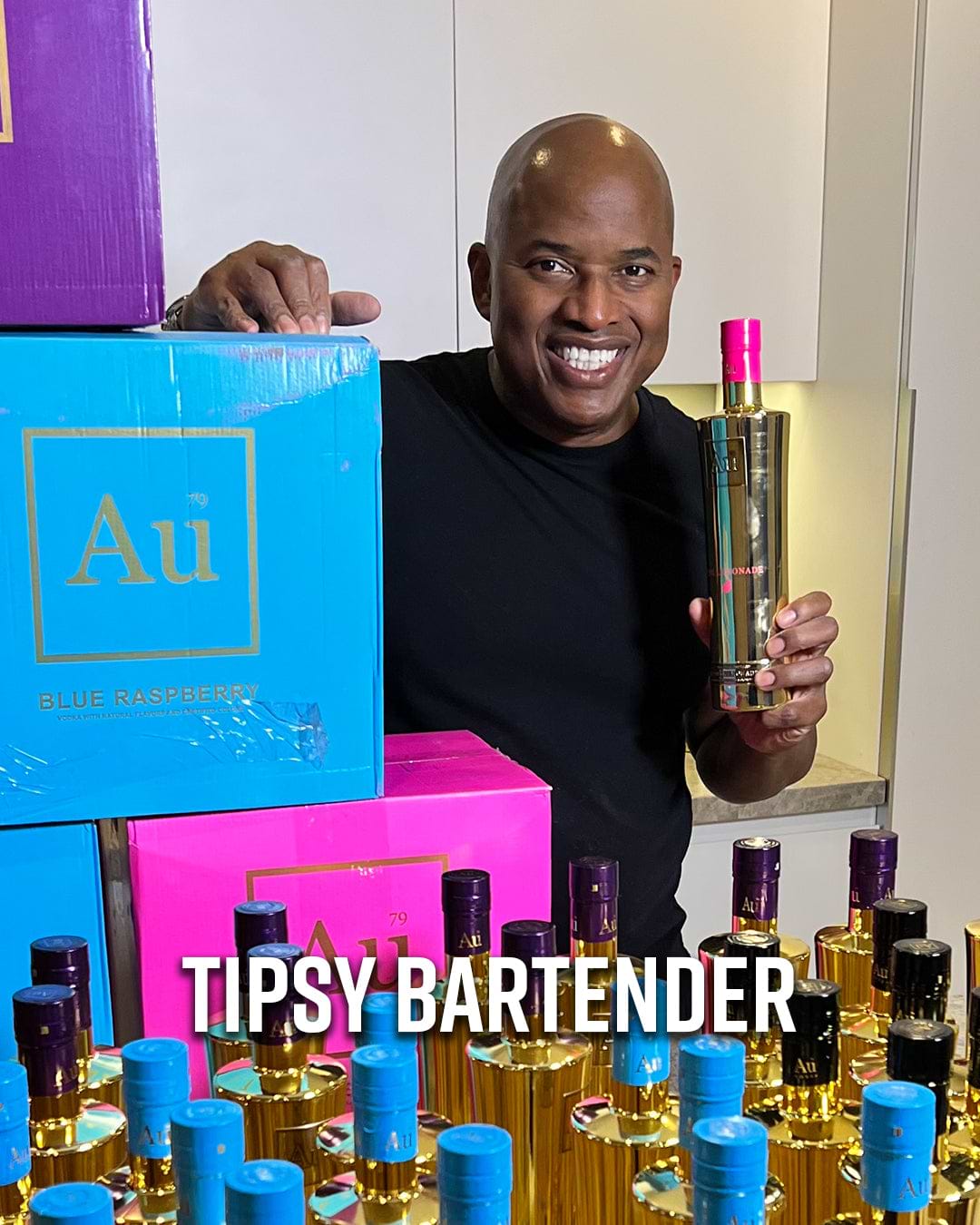 Tipsy Bartender holding a bottle of Au Vodka Pink Lemonade with boxes of Au Vodka Blue Raspberry