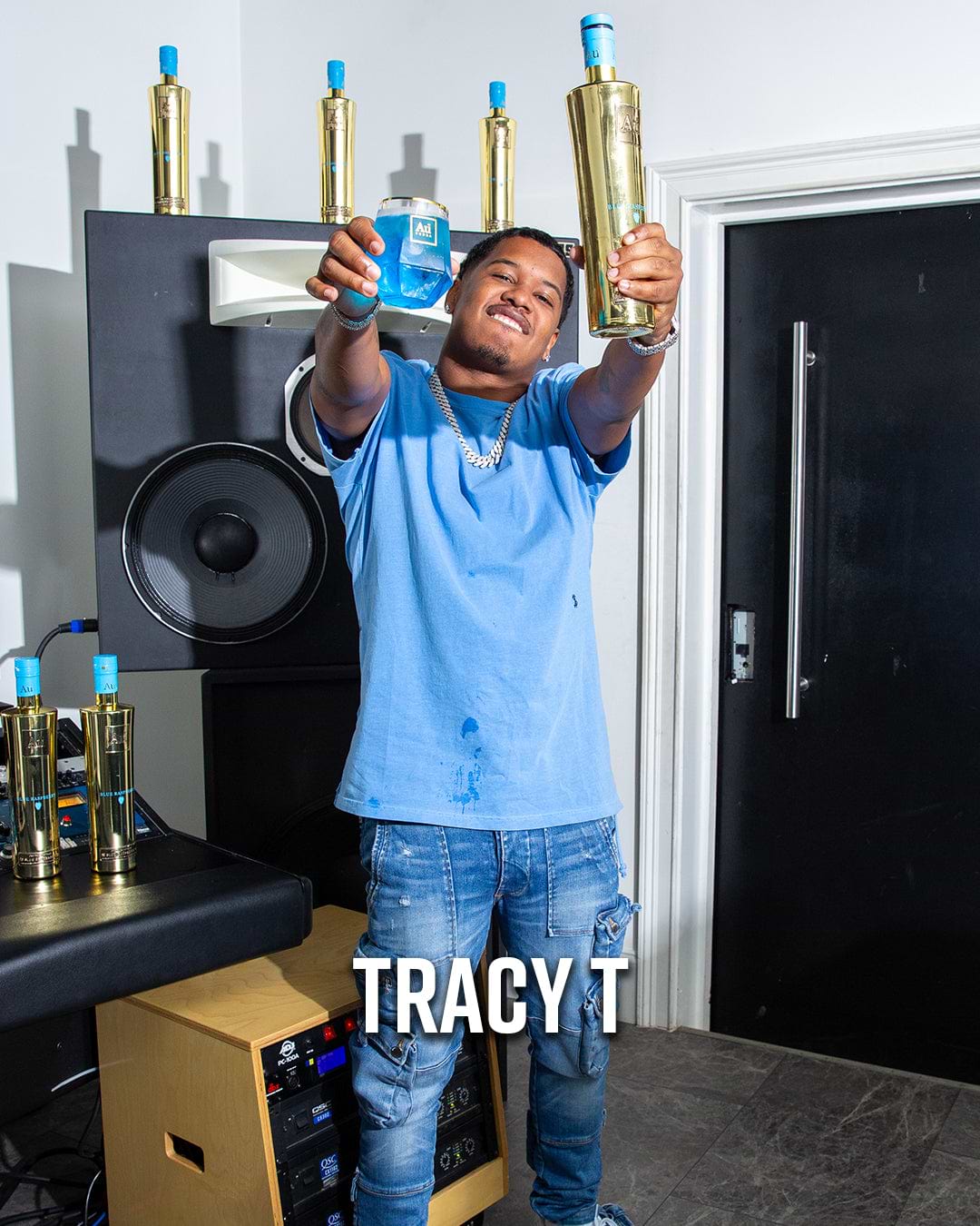Tracy T holding a bottle of Au Vodka Blue Raspberry and a glass of blue liquid