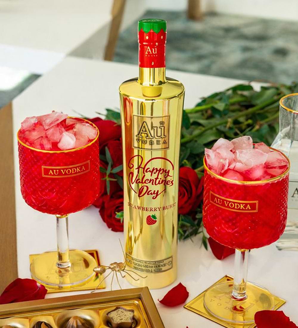 Au Vodka Strawberry Burst bottle with two red glasses filled with ice and red roses