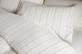 Close-up of a neatly made bed with the nkuku Anta Hemp & Cotton Duvet Cover in sage green, paired with matching pillow and sheet for a fresh, airy look. Bedding features breathable hemp-cotton blend for comfort and style.