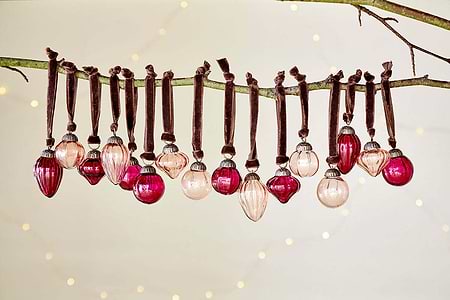 The nkuku Adisa Bauble Jar - Ruby & Copper (Set of 16) brings festive charm to any branch with its mini baubles.