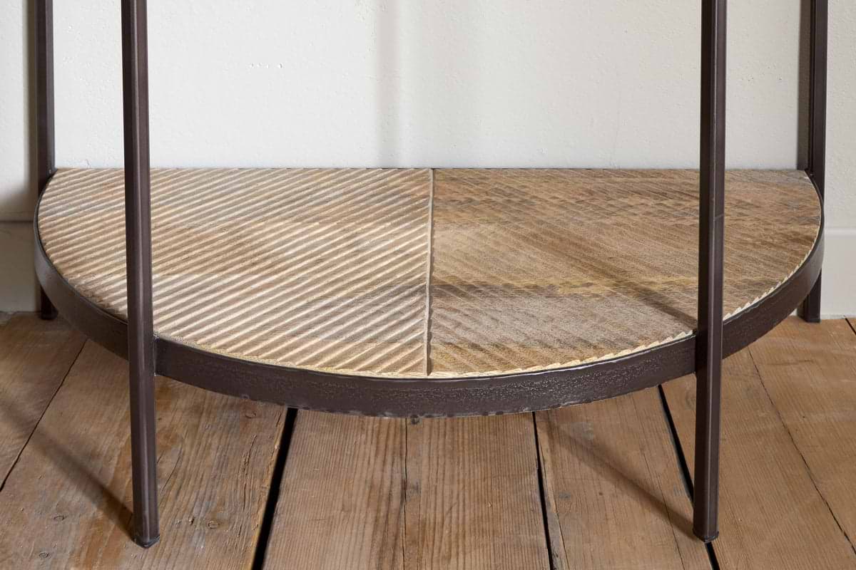 A close-up of the nkuku Aasha Mango Wood Half Moon Console Table in Natural, showcasing its ridged texture and four dark metal legs, displayed on a wooden floor.