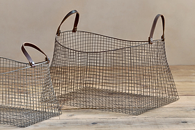 The Adah Iron Baskets - Brown (Set of 2) by nkuku feature brown leather handles and stackable storage; the larger, conical basket is open on the right, while the smaller one is partially visible on the left.