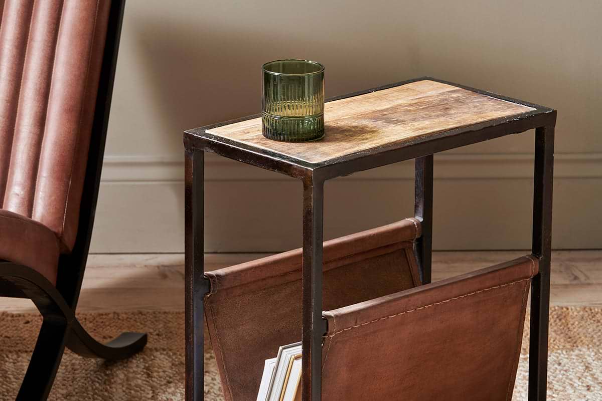 The nkuku Alera Side Table features a rustic leather base, mango wood top, and sturdy iron frame. It’s perfect for holding a green glass above and includes space below for storing magazines in style.