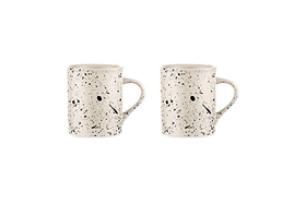 Two nkuku Ama Mug - Tall ceramic mugs feature a white base with a black splatter finish and handles. Each artisan mug displays a minimalist face—two black dots for eyes and a short black line for the mouth.