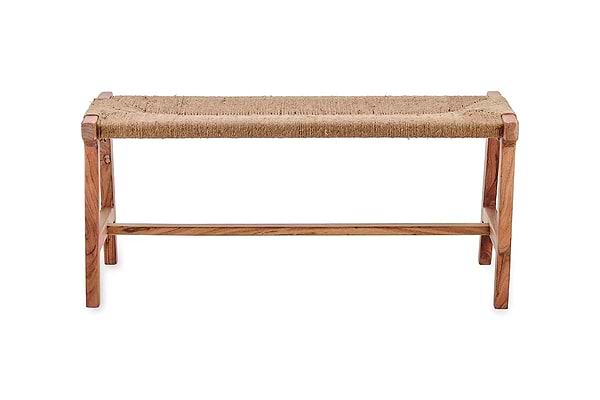 The Amhara Acacia & Jute Woven Bench by nkuku features a minimalist design with four simple legs, a horizontal support bar, and a woven jute seat. Its light acacia wood and natural textures create a rustic contrast against any space.