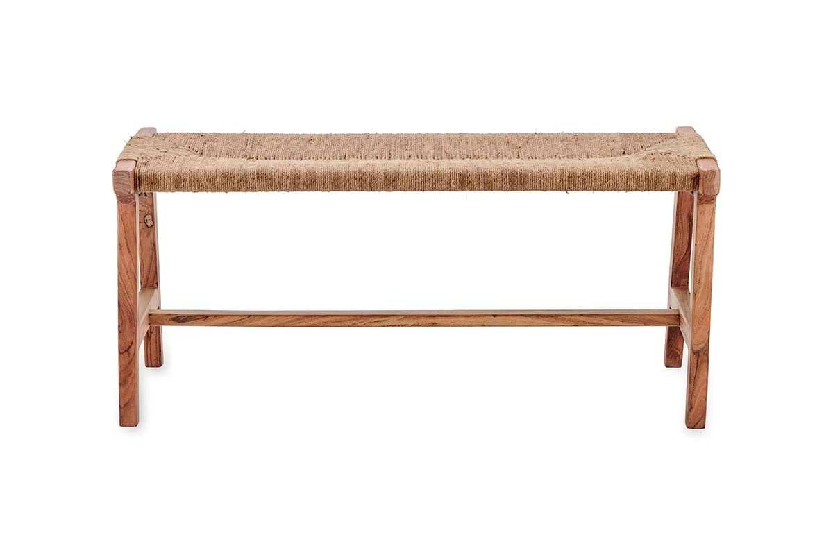The Amhara Acacia & Jute Woven Bench by nkuku features a minimalist design with four simple legs, a horizontal support bar, and a woven jute seat. Its light acacia wood and natural textures create a rustic contrast against any space.