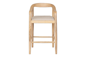 The nkuku Anbu Mango Wood Upholstered Counter Chair - Natural features a light mango wood frame, curved open-backrest with armrests, and a beige fabric seat. Supported by four straight legs with bars, it’s ideal as a stylish kitchen counter stool.