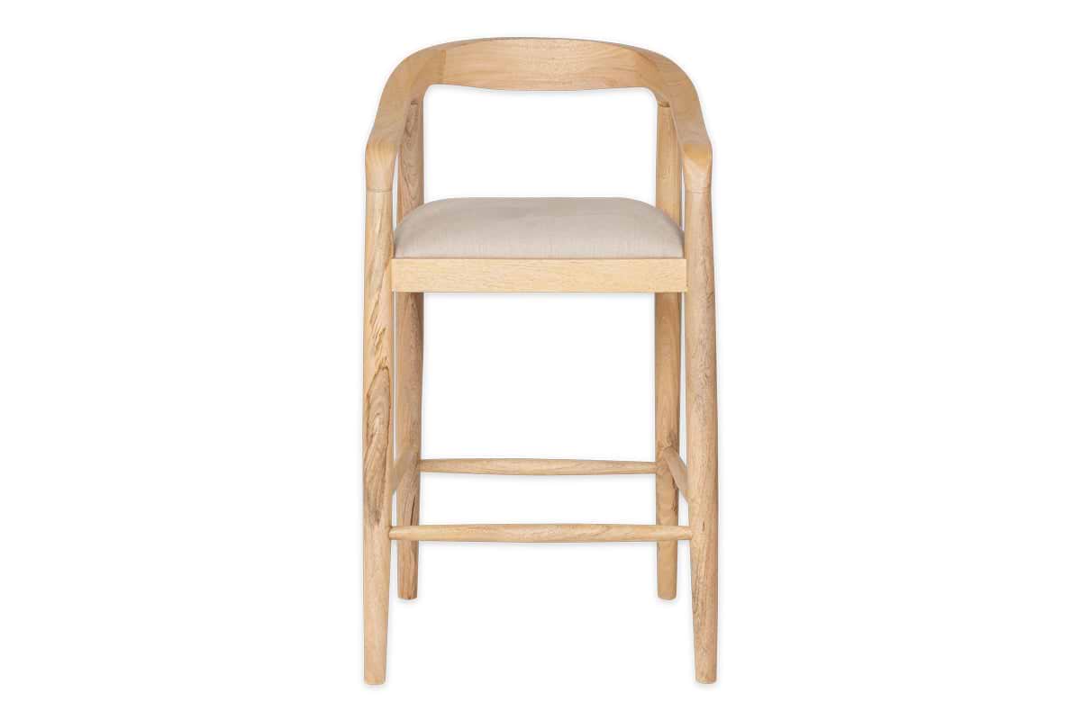 The nkuku Anbu Mango Wood Upholstered Counter Chair - Natural features a light mango wood frame, curved open-backrest with armrests, and a beige fabric seat. Supported by four straight legs with bars, it’s ideal as a stylish kitchen counter stool.