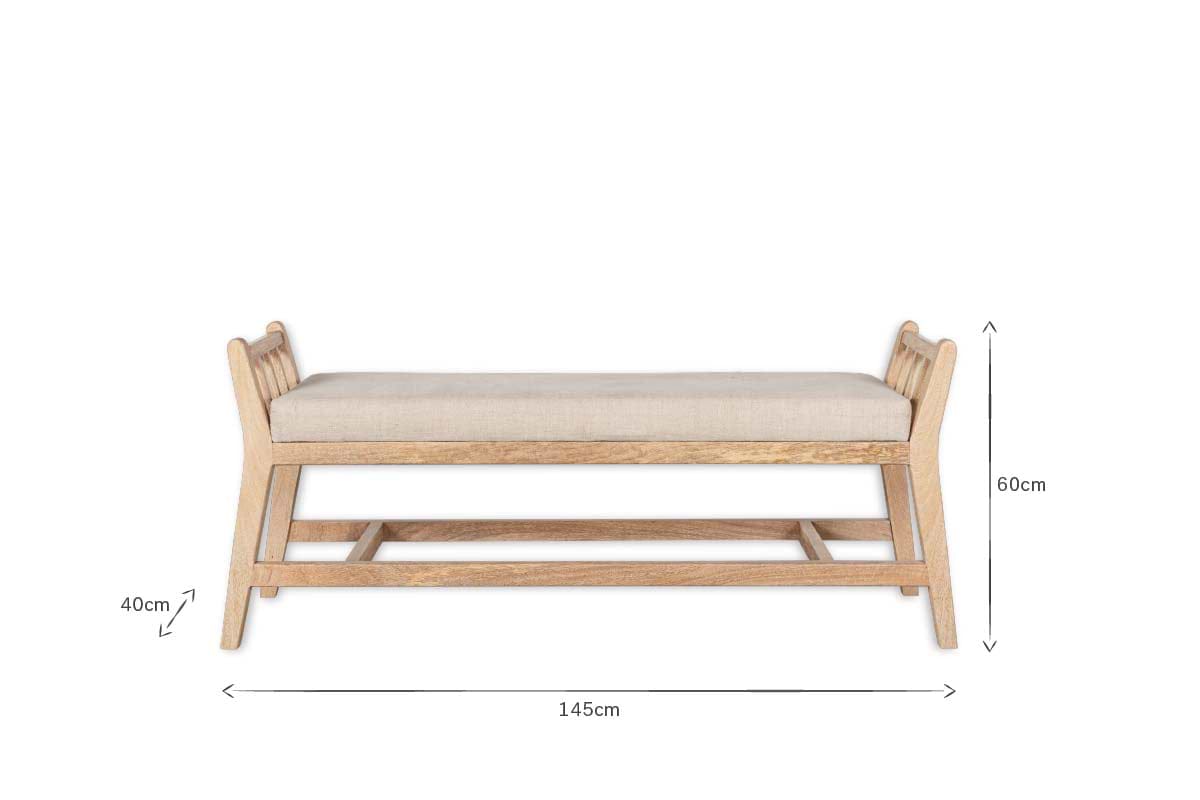 The Avanthi Upholstered Sleigh Bench by nkuku features hand-carved mango wood, a cushioned linen seat, and slatted backrests. Dimensions: 145cm length, 60cm height, 40cm seat height.