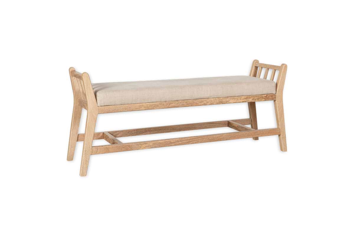 The Avanthi Upholstered Sleigh Bench by nkuku features a hand-carved mango wood frame in natural finish, beige cushioned seat, open slatted sides, angled legs, and wooden support bars for a modern yet traditionally crafted look.