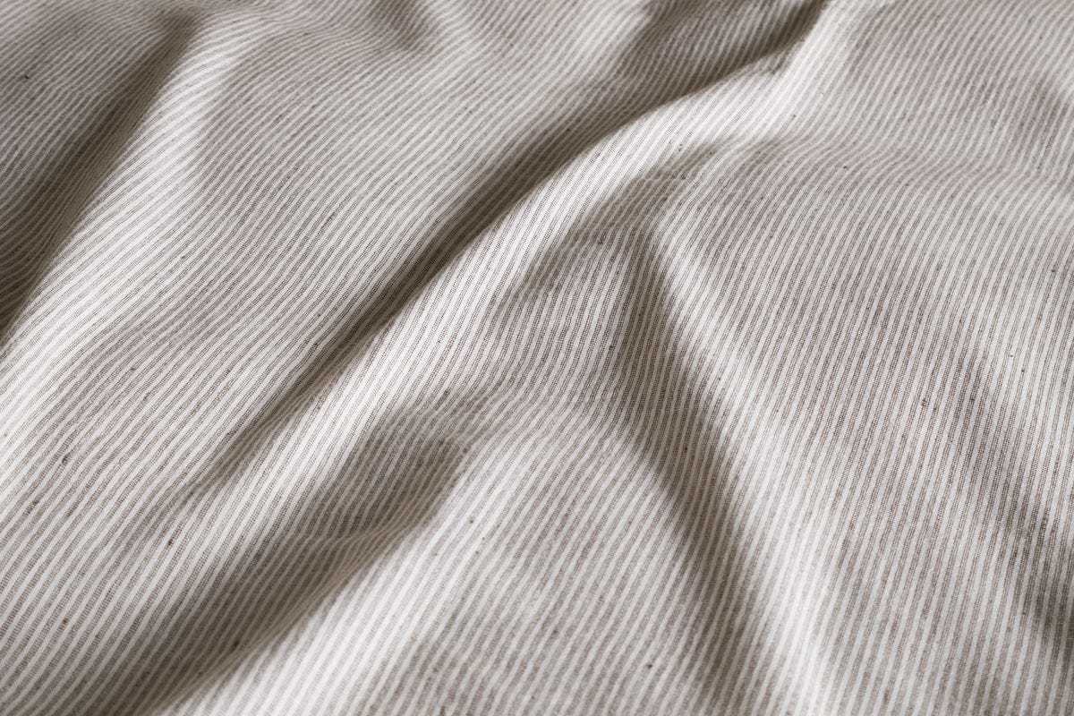 Close-up of the Borba Hemp & Cotton Duvet Cover in Espresso by nkuku, featuring textured beige and white stripes for a breathable, comfortable nights sleep.