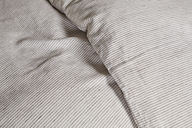 Close-up of the nkuku Borba Hemp & Cotton Duvet Cover in Espresso, featuring breathable, soft fabric with fine beige and white horizontal stripes and a slightly rumpled, textured look.