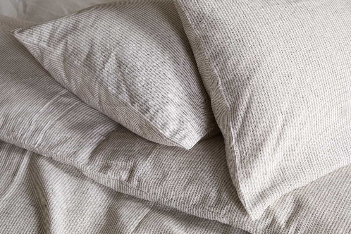 Two pillows in nkukus Borba Hemp & Cotton Housewife Pillowcases in Espresso are neatly arranged on a bed, creating a soft and cozy look.