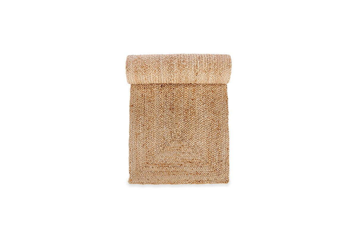 The nkuku Braided Hemp Table Runner features coarse, woven natural fibers in a beige-tan hue, offering handcrafted style—ideal for adding rustic charm to your tablescape. Shown rolled on a white background.