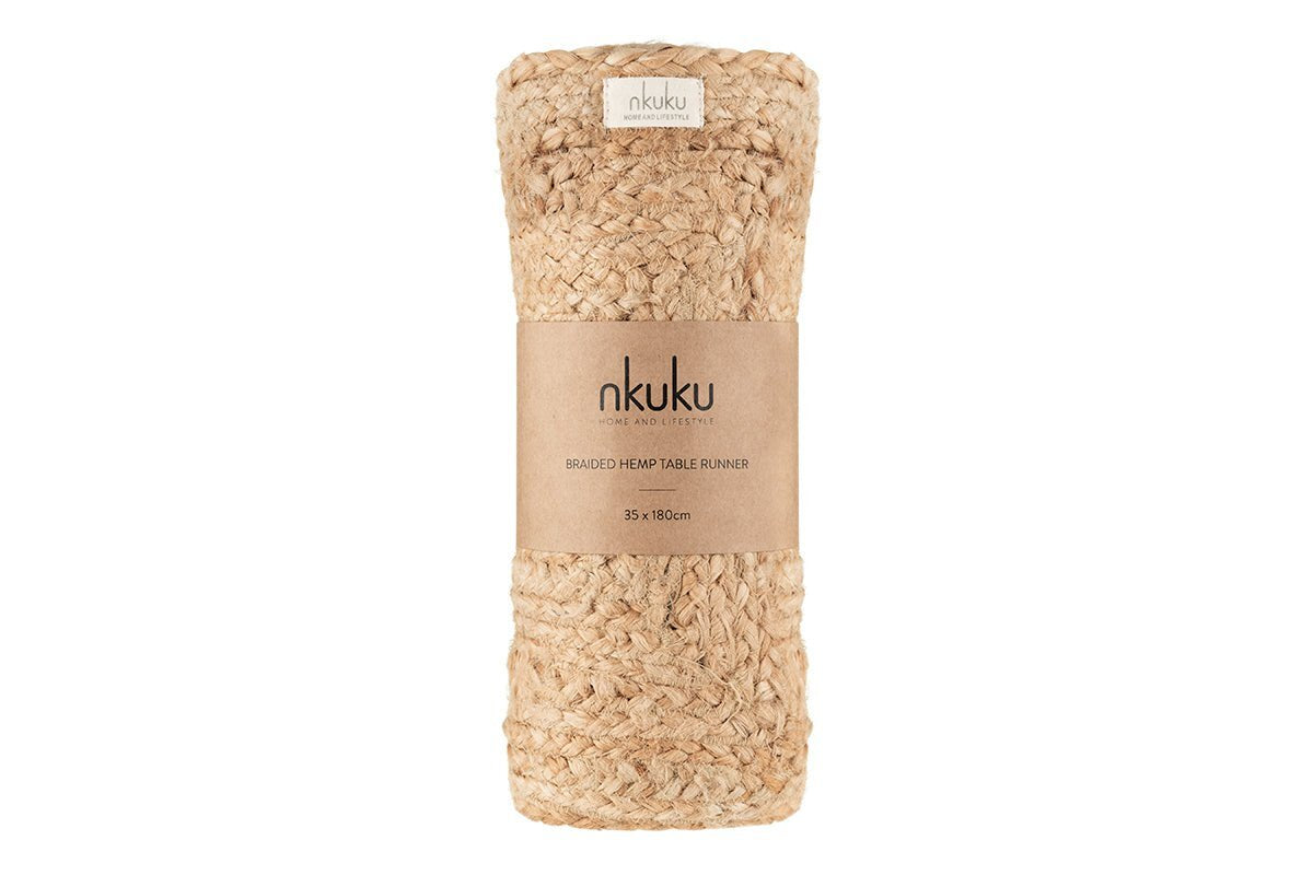 The nkuku Braided Hemp Table Runner (35 x 180cm), with its beige natural texture and artisan charm, is wrapped in a brown paper label and brings ethical, handmade style to any tablescape.