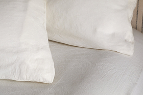 A close-up of two Cela Hemp & Cotton Housewife Pillowcases by nkuku in natural, featuring breathable fabric and a soft, clean look on a neatly made bed with white linens.