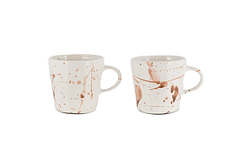 The nkuku Canela Mug - Dusty Terracotta (Set of 2) features two ceramic mugs with handles, each showcasing a unique brown splatter pattern for an artisanal look. The mugs are displayed against a plain white background.