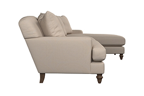 Side view of the Deni Large Corner Sofa - Brera Linen Pebble by Nkuku, a beige large corner sofa with plush cushions and wooden legs, featuring a right-side chaise lounge extension and washed linen upholstery, all set against a white background—a fine example of British quality furniture.