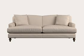 The Nkuku Deni Large Corner Sofa in Brera Linen Smoke showcases British quality craftsmanship with its simple and elegant design. Upholstered in beige linen, this sofa features two seat cushions, two back cushions, slightly curved armrests, and dark wooden legs. It is set against a plain light background.