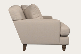 Side view of the Nkuku Deni Large Corner Sofa in Brera Linen Smoke, showcasing two seat cushions, two back cushions, and exposed dark wooden legs; set against a solid off-white background that highlights British quality craftsmanship.